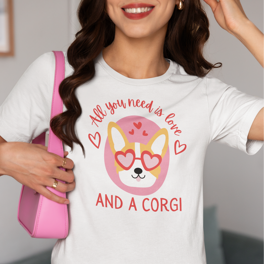Person wearing a white t-shirt with a Valentine's Day corgi graphic and text, All you need is love and a corgi, holding a pink bag.